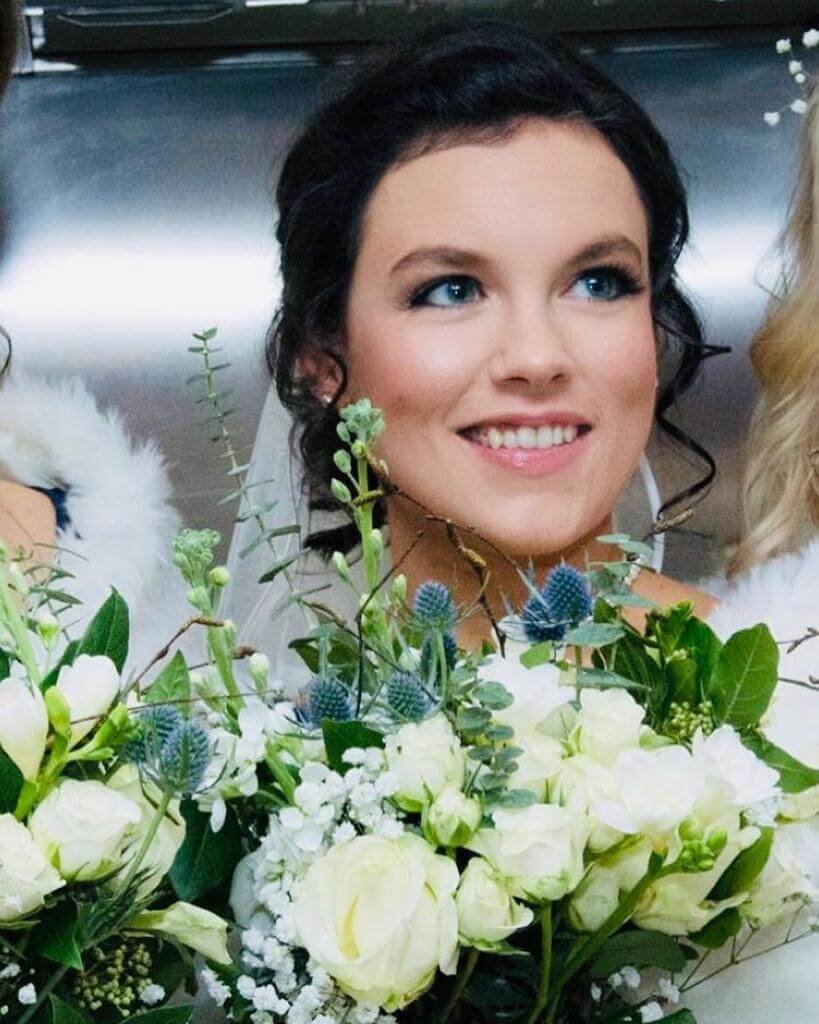 Bride with bouquet featuring cream roses and blue thistles